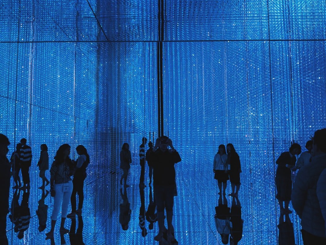 a-group-of-people-standing-in-front-of-a-blue-wall-1k4gfl6i63e