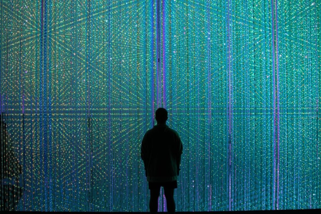 a-person-standing-in-front-of-a-wall-of-lights-naxa1dh-jgg